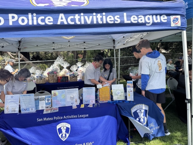 San Mateo PAL booth with staff and visitors at an outdoor community event.