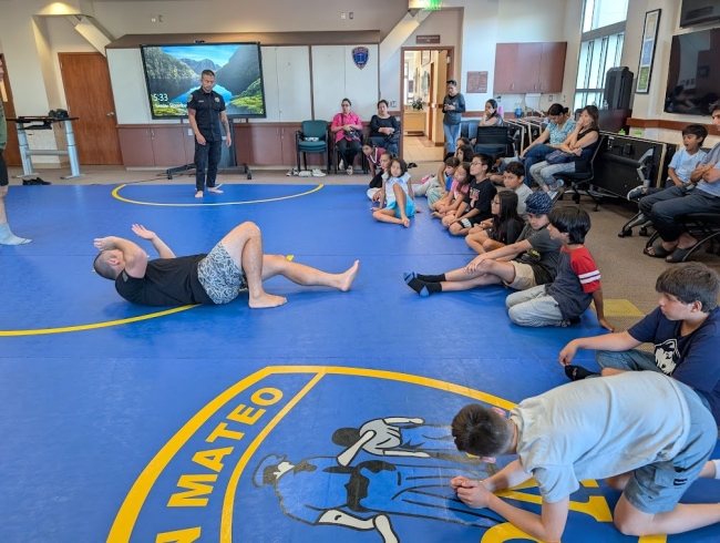 Children watching a police officer lead a youth safety demonstration.